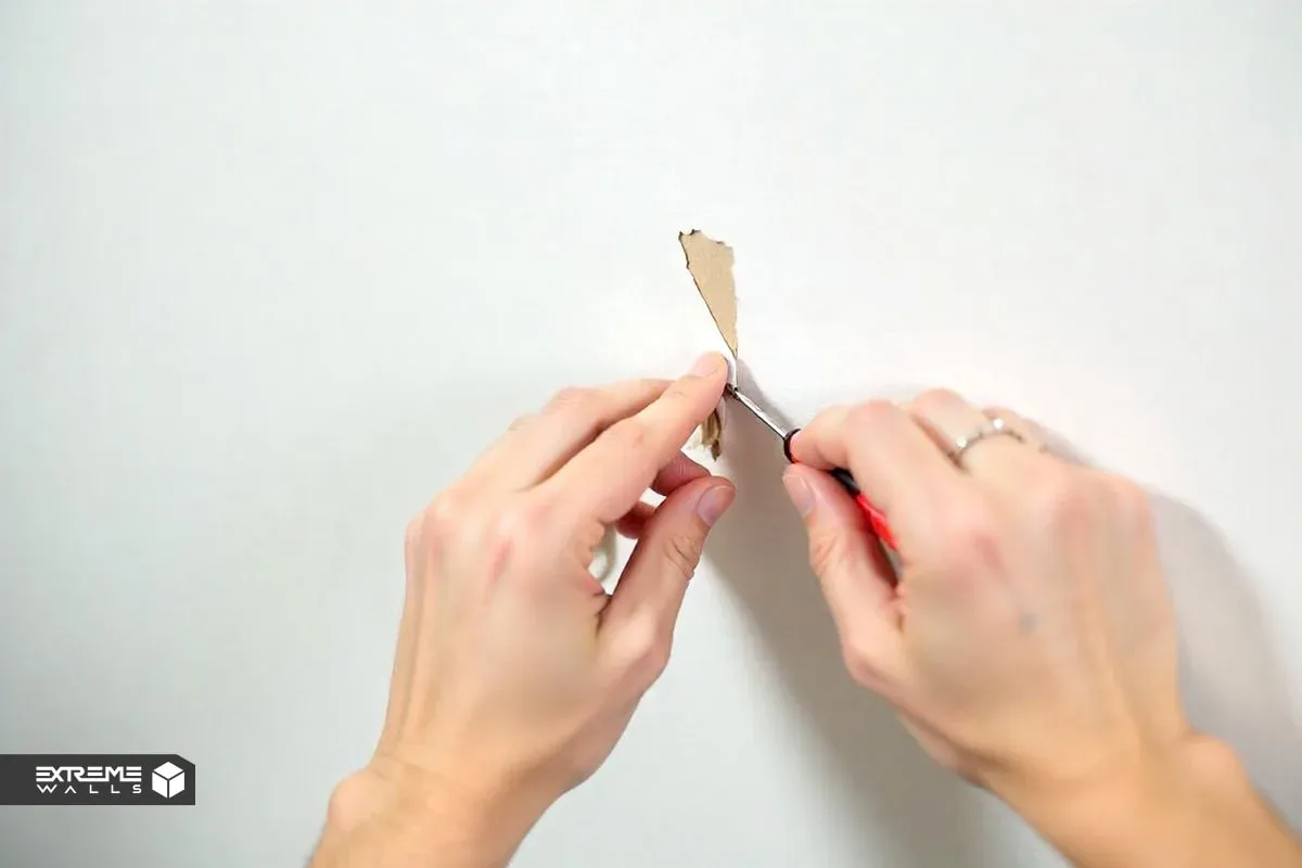 کاربردی ترین روش های ترمیم کاغذ دیواری پاره شده و آسیب دیده 10 تصویر یک دست در حال چسباندن تکهای از کاغذ دیواری با طرح مشابه روی سوراخ دیوار