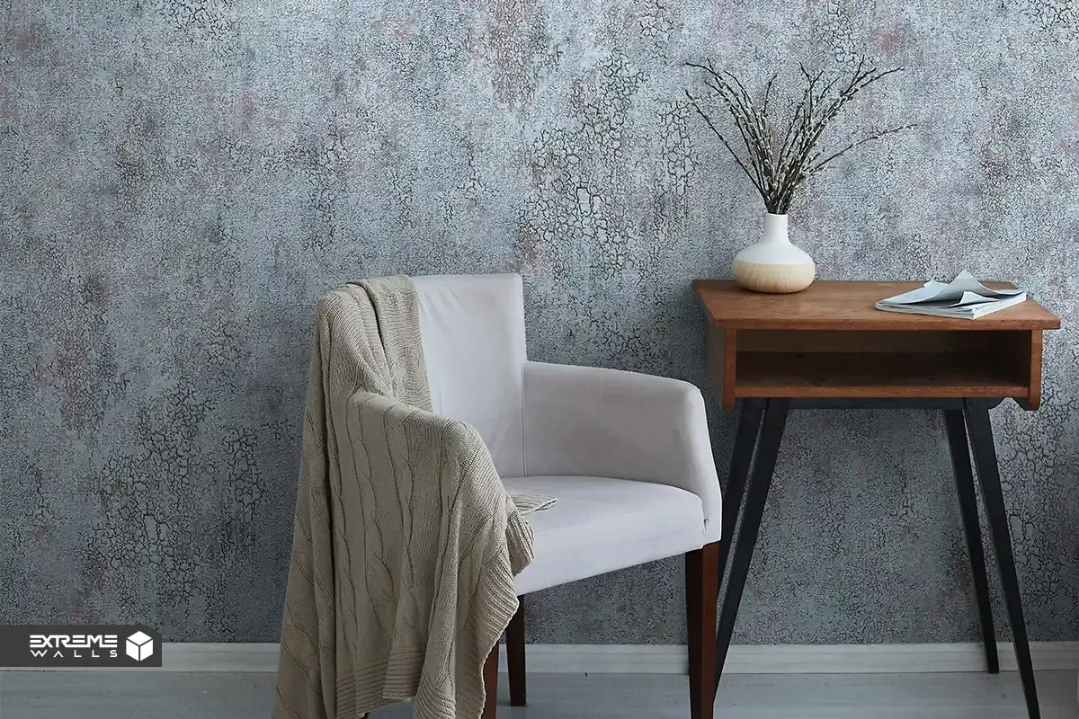 کاغذ دیواری با بافت برجسته و طرح پتینه کنار مبل طوسی در دکوراسیون کلاسیک